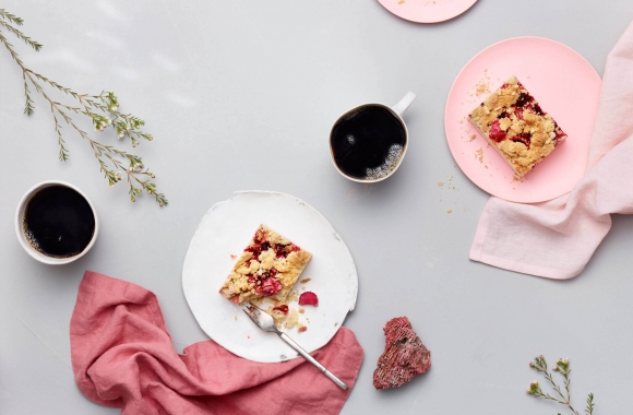 Raparperipiirakka ja kahvia tarjolla pöydällä, jossa pinkkejä somisteita